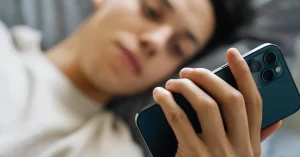 Young Guy Browsing Mobile Phone on Bed